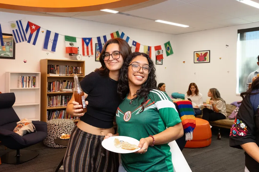 Two students standing and smiling together.